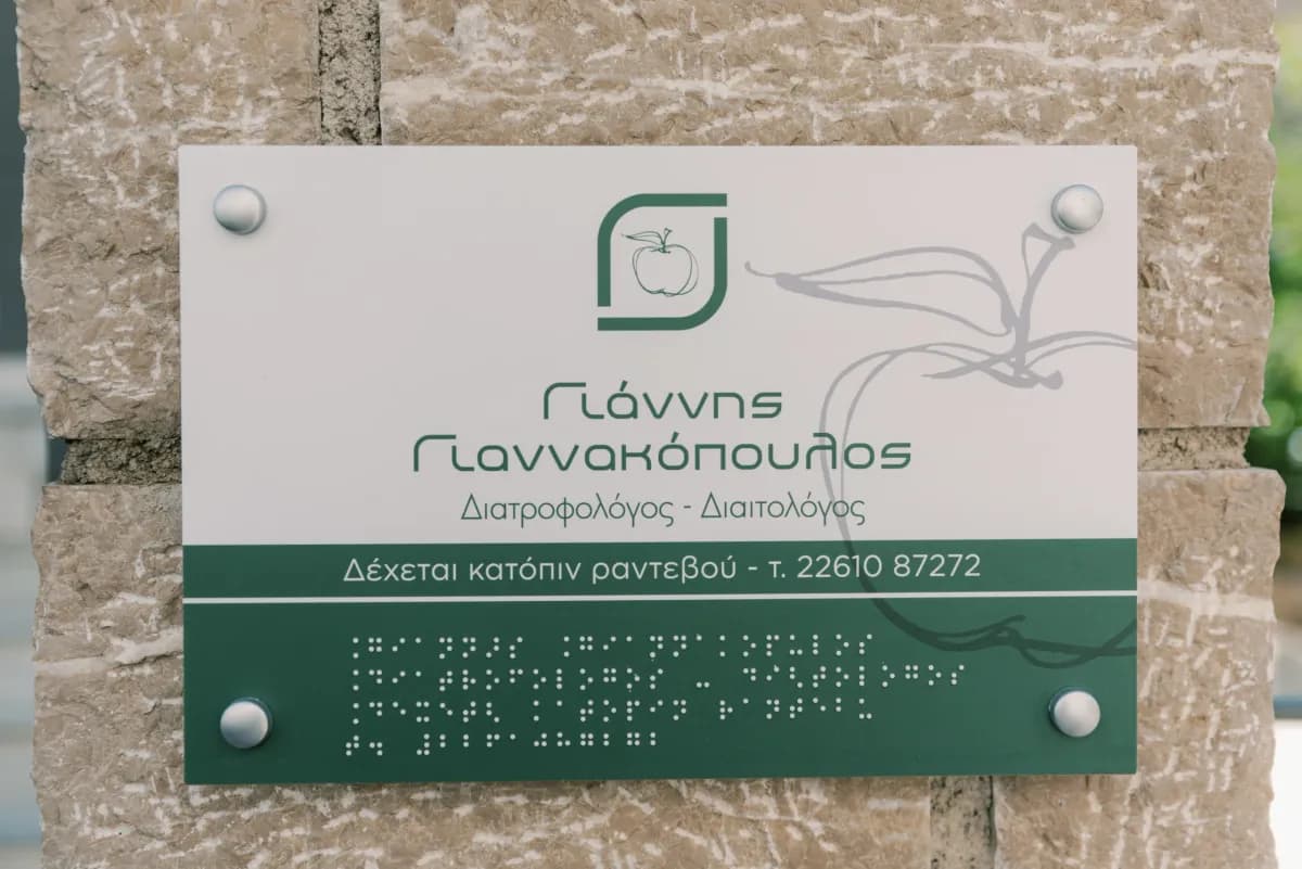 Η πινακίδα του γραφείου σε πέτρινη κολόνα, με γραφή Braille